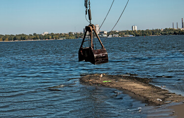 The bucket of a special dredger cleans the artificial island. Ecological disaster in the coastal waters of the Dnieper River