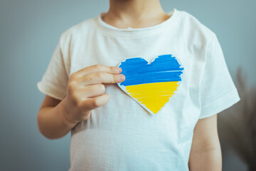 Hand holding a heart made from the flag of Ukraine blue yellow on an isolated white background. Concept of victory of Ukraine, independence of Ukraine. Patriotism and love for the country. My homeland