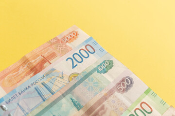 Money of Russia. Banknotes and coins on yellow background. Close-up of Russian rubles of various denominations. Finance concept