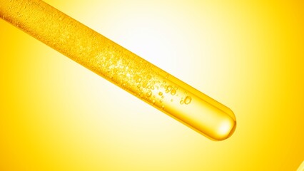 Oil being injected in inclined test tube with transparent liquid on yellow background