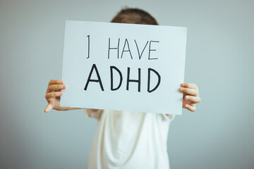 Young boy holds ADHD text written on sheet of paper. ADHD is Attention deficit hyperactivity disorder. Close up. Attention Deficit Hyperactivity Disorder or ADHD