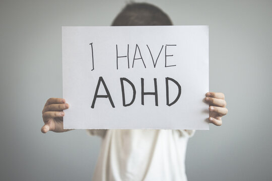 Young boy holds ADHD text written on sheet of paper. ADHD is Attention deficit hyperactivity disorder. Close up. Attention Deficit Hyperactivity Disorder or ADHD