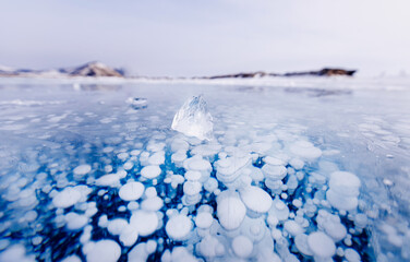 Gas methane bubbles frozen in winter ice of lake Baikal, abstract background