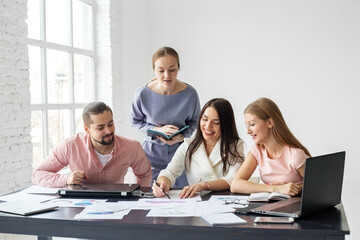 Colleagues work together in the office using computers, notepads, graphs. Business and marketing.