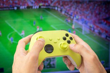 Man holding game controller playing football game. © miglagoa