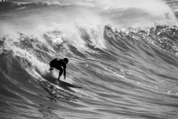 Gray scale of a surfer surfing on a big wave in ocean