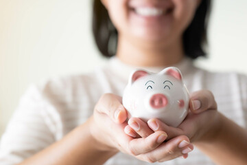 Woman holding a piggy bank with both hands with smile. Saving money for future, Investment concept
