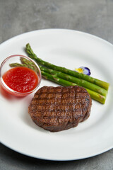 Grilled asparagus with hollandaise sauce steak on a white plate.