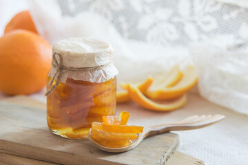 Homemade candied peels orange confiture in glass jar on light background, selective focus