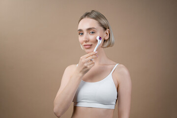 Beautiful woman using electronic face roller device, doing skin rejuvenation massage. Concept of beauty and self care.