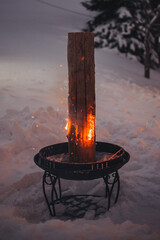 Close-up shot of a Swedish fire log, long burning log in a snowy land on a blurred background