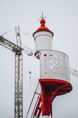 Vertical shot of a high white red observer next to a high metal crane against a light sky