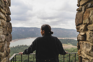 Chica joven guapa en balc&oacute;n de piedra mirando zona monta&ntilde;osa en pueblo blanco andaluz