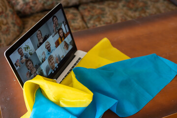 Flag of Ukraine on the background and wide digital screen of laptop with video conference. War with Russia. Cyber attack, sanctions, economic collapse. Message for world peace.