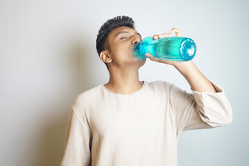 Young man drinking from a blue water bottle