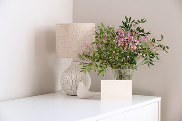 Bunch of flowers in vase, scandinavian style table lamp, bird , blank greeting card mockup on white...