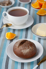 Rye bun and breakfast butter with tea and orange