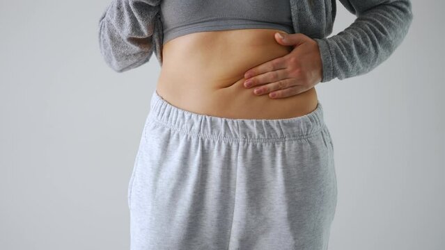Woman compressing the skin on her stomach checking for cellulite and excess subcutaneous fat