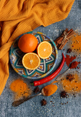Vibrant still life with oranges and spices. Colorful image of aroma spices. Dark grey textured background with copy space. 