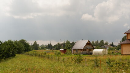 Fototapeta na wymiar Beautiful rustic summer landscape. Old wooden log houses. Vologda region