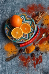 Vibrant still life with oranges and spices. Colorful image of aroma spices. Dark grey textured background with copy space. 