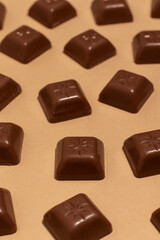 Square pieces of chocolate on a beige background.