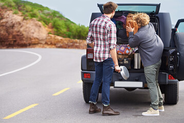 We need a bigger truck. Shot of a two people stopped at the side of the road and repacking their...