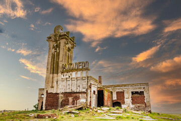 Ruined building of slaughterhouse Matadero in Villa Epecuen village against a blue cloudy sky