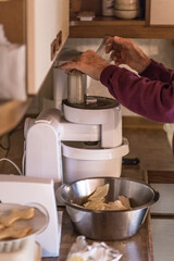 Alter Mann Opa mit H&auml;nde benutzt eine K&uuml;chemasche und schneidet h&auml;ckselt Wei&szlig;kohl f&uuml;r einen Salat in einer K&uuml;che, Deutschland