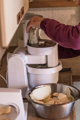 Alter Mann Opa mit Hände benutzt eine Küchemasche und schneidet häckselt Weißkohl für einen Salat in einer Küche, Deutschland