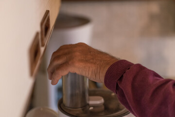 Fototapeta na wymiar Alter Mann Opa mit Hände benutzt eine Küchemasche und schneidet häckselt Weißkohl für einen Salat in einer Küche, Deutschland
