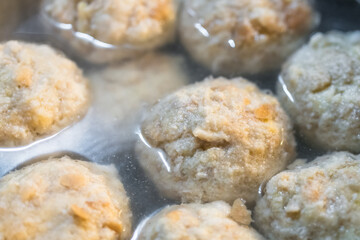 Nahaufnahme von selbst gemachten Semmelknödel Knödel in heißem Wasser mit Kochtopf auf Herd in der Küche, Deutschland 