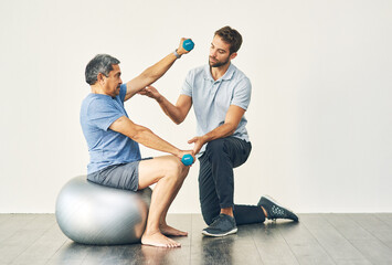 Keep your form. Full length shot of a young male physiotherapist assisting a senior patient in...