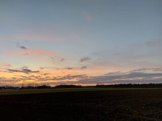 Herrlicher Sonnenuntergang. Die Natur versinkt in Dunkelheit. In der Ferne sieht man Silhouetten von verzweigten Laubbäumen ohne Blätter. Das Tageslicht verblasst am Horizont. Die Dunkelheit im Morgen