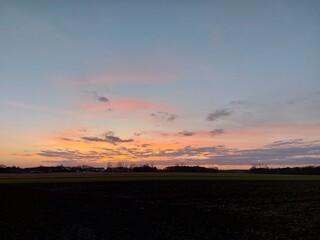 Herrlicher Sonnenuntergang. Die Natur versinkt in Dunkelheit. In der Ferne sieht man Silhouetten von verzweigten Laubbäumen ohne Blätter. Das Tageslicht verblasst am Horizont. Die Dunkelheit im Morgen