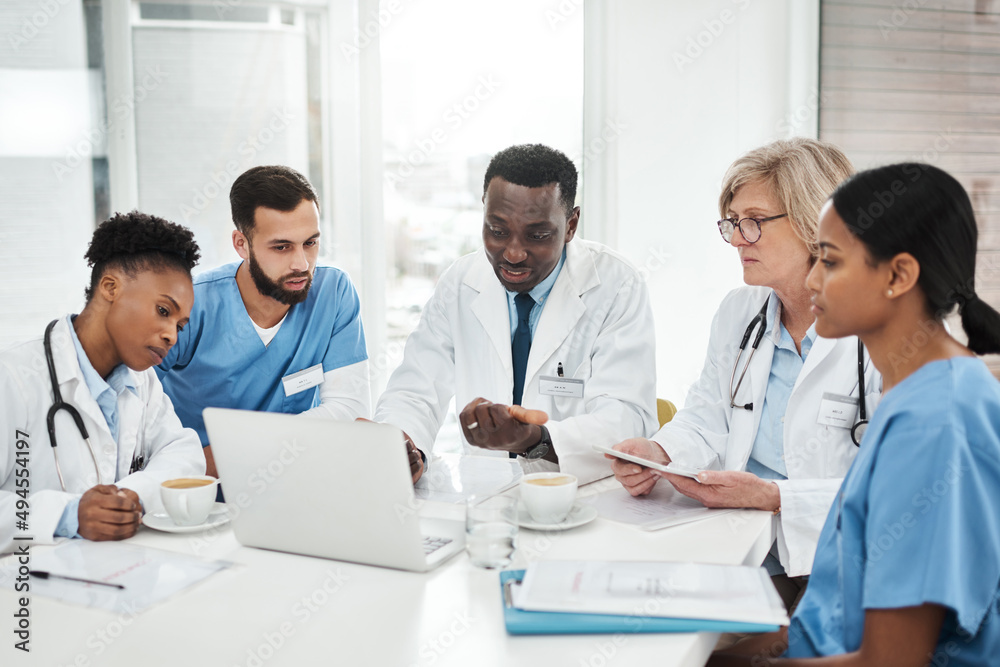 Poster working together for their patients. shot of a group of medical practitioners using a laptop during 