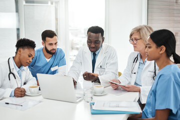 Working together for their patients. Shot of a group of medical practitioners using a laptop during a meeting in a hospital boardroom.