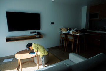 A boy in a yellow shirt looks down at a picture he drew on a blackboard in his resort room on the weekend