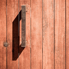 A modern natural wood door with metallic handle closeup, space for your text or logo
