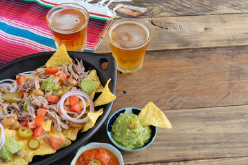 Black ceramic tray of nachos with meat and beer sauce bowls with mexican decoration. Copy space. Mexican kitchen concept.