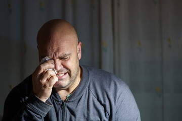 Middle-aged man crying alone at home.