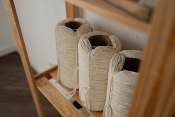 Fototapeta na wymiar Rope of natural color for weaving macrame products. The material in the bobbins is on a wooden rack.