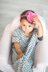 Cute little girl sitting on small armchair and smiling at camera.