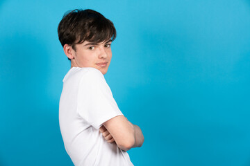 Portrait of shy teenager boy on blue background