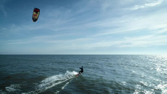 In this aerial drone camera shot you can see fearless extreme sport lover &ndash; kiteboarder riding ocean water with his kite flying in the blue sky.