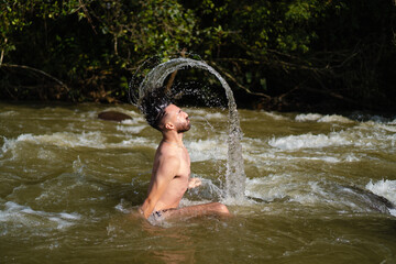 portrait of a young latin man in the river naked, reconnected with nature and the environment.