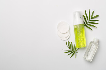 Foaming facial cleanser and micellar water on color background, top view