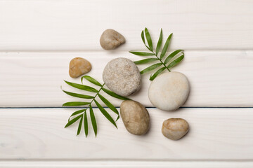 Fototapeta na wymiar Spa stones and leaves on wooden background, top view