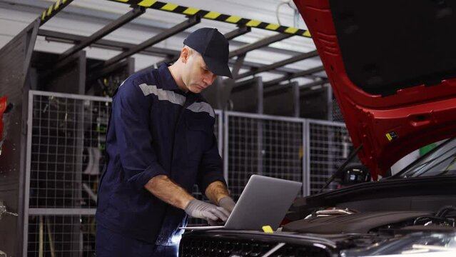 Auto mechanic uses a laptop while conducting diagnostics test