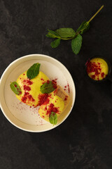 Cottage cheese casserole or pudding served with mango puree cream and mint in eco paper box. Healthy breakfast food, sweet snack or meal rich in Protein, Calcium. Restaurant dish delivery concept. 